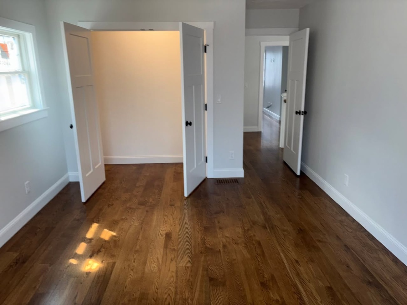Sunlit bedroom with warm refinished oak hardwood flooring
